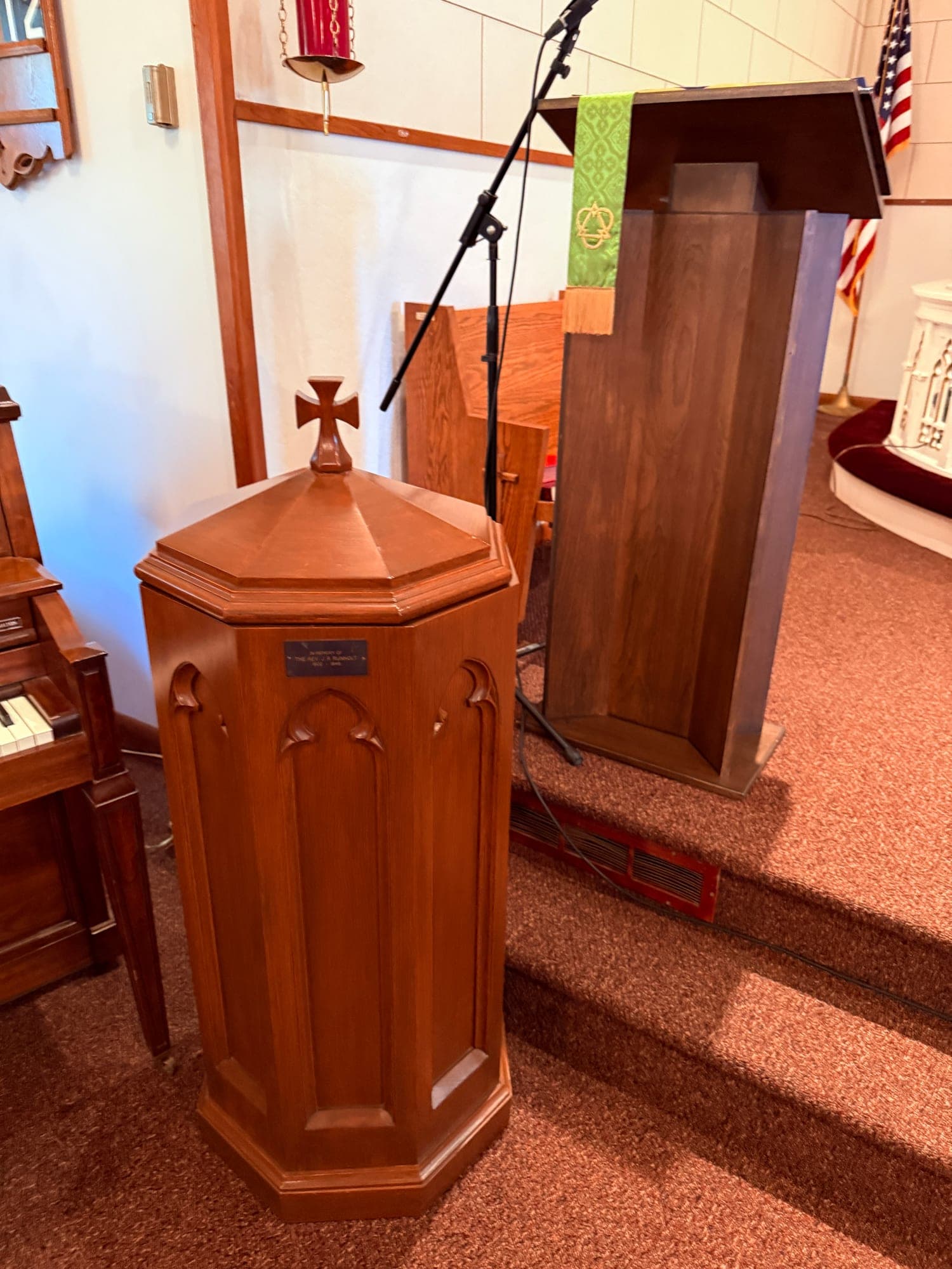 The wooden baptismal font at Calvary Lutheran Church, topped with a carved cross